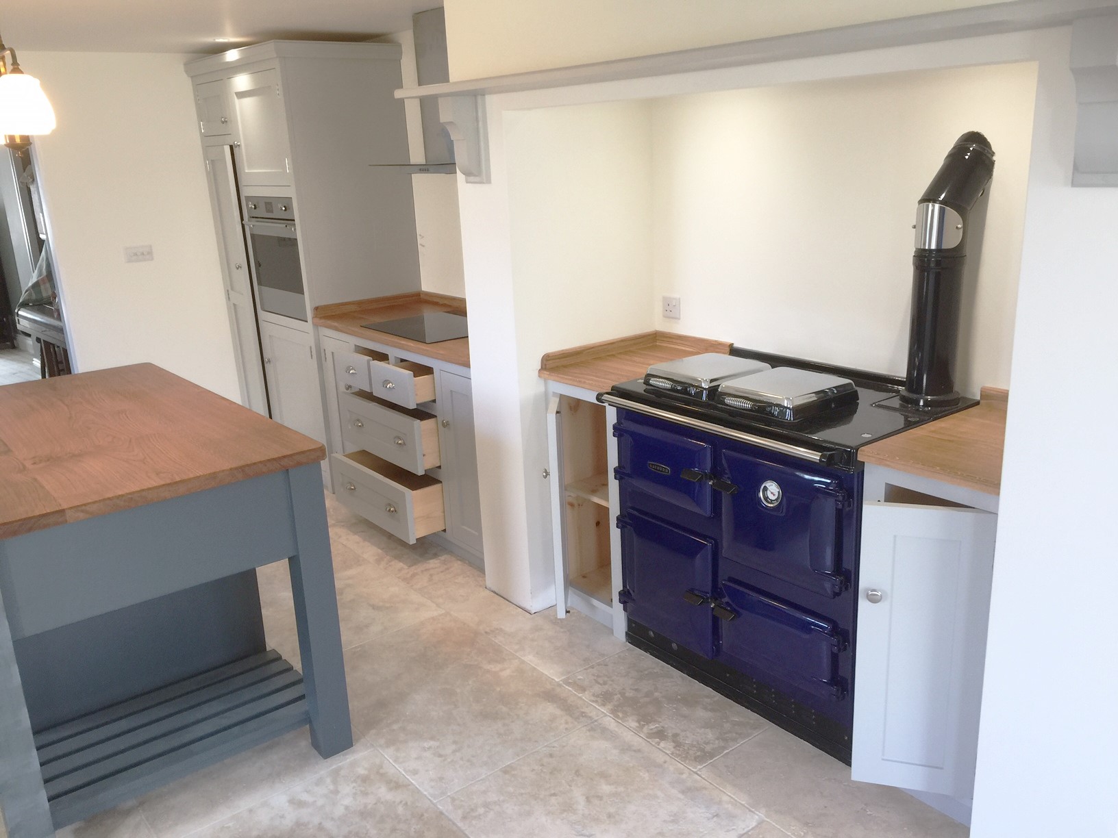 Individually tailored shaker style fitted kitchen hand made from solid wood painted in Farrow & Ball pavillion grey. Fully bespoke island site with wide plank solid oak surface top.